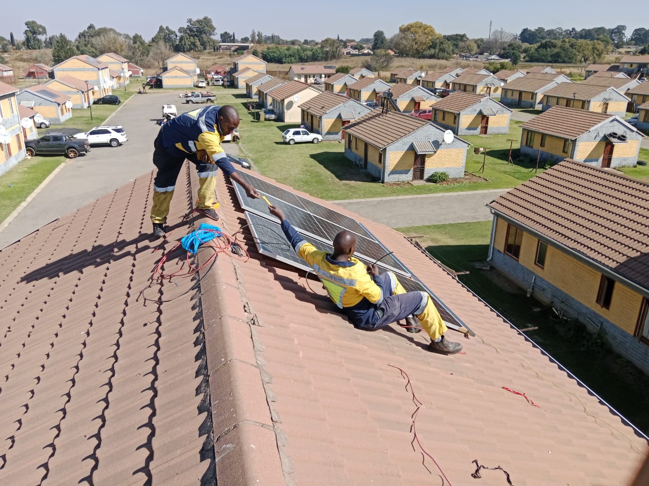Technicians installing solar panels on a tiled roof